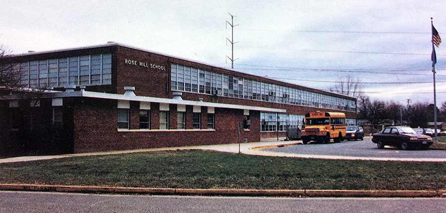 Color photograph of Rose Hill Elementary School taken in 1993. A school bus is parked in front of the building. 